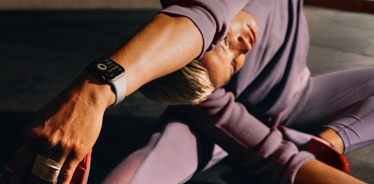 Une femme portant une Apple Watch fait des étirements.
