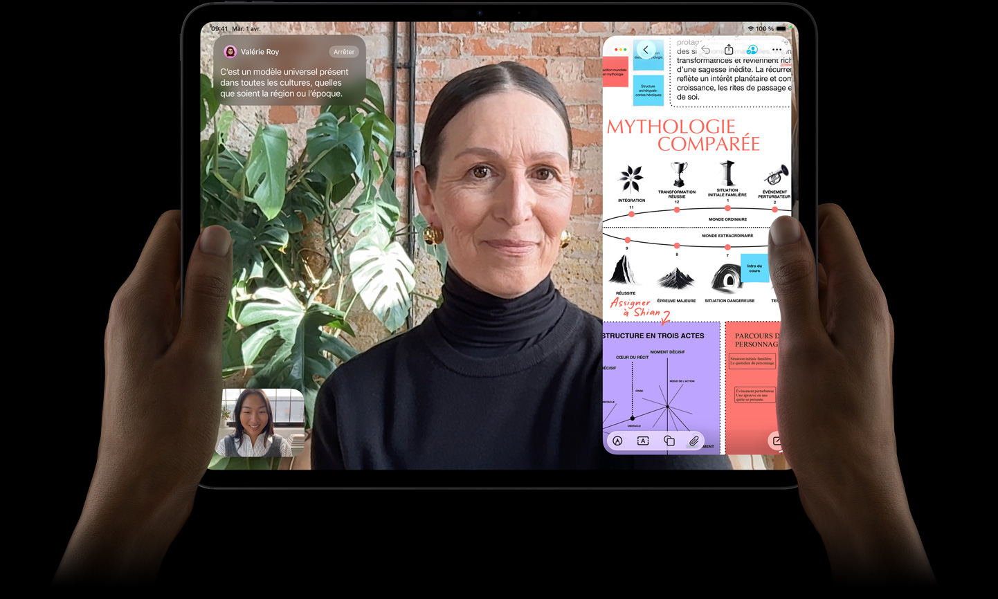 Un iPad Pro, face avant, noir infini, mains tenant les côtés gauche et droit en orientation paysage, coins arrondis, bordure d’écran noire, écran affichant une conversation FaceTime traduite en direct, et une app éducative montrant une présentation sur la mythologie comparée avec du texte, des diagrammes et des notes manuscrites