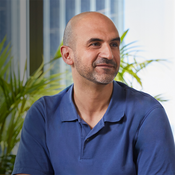 Ahmed 坐在室內，微笑望向左邊的鏡頭。