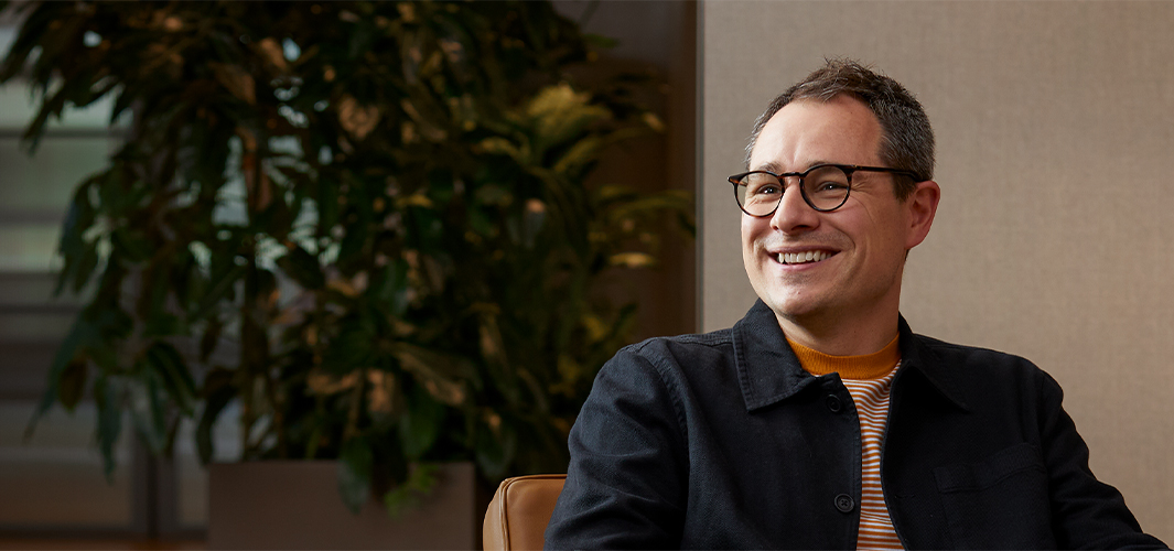 Dan 坐在扶手椅上，微笑望向右邊的人。