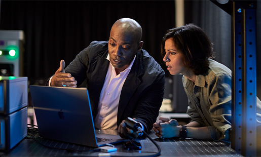 Mike en een collega zijn in een laboratorium en kijken samen naar een MacBook.