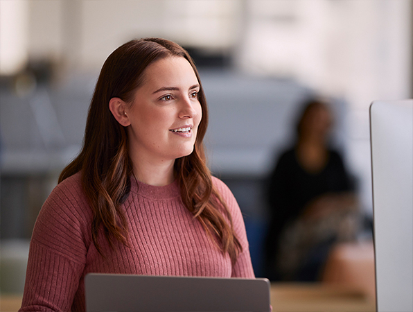 Een medewerker van Apple Software & Services werkt op haar MacBook en kijkt opzij.