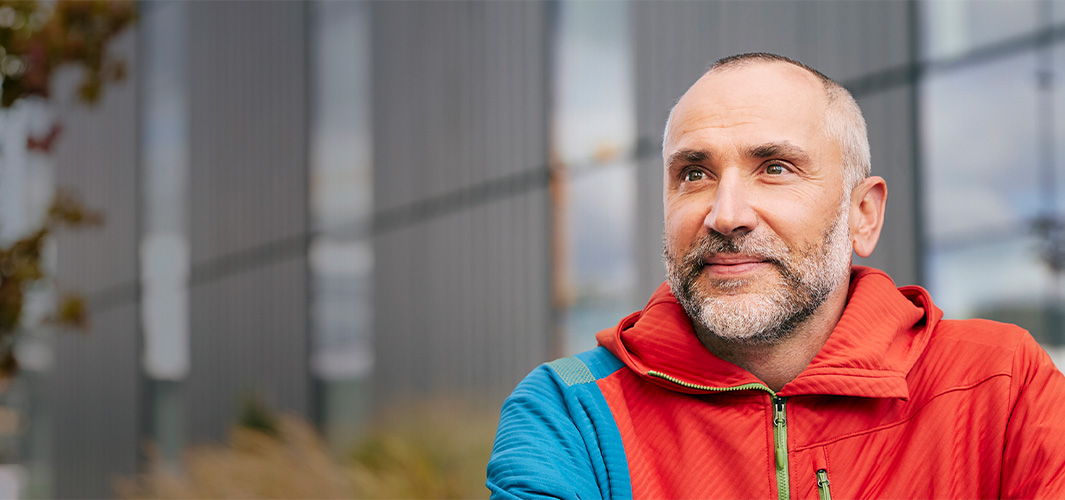 Dragos zit buiten en kijkt lachend opzij.