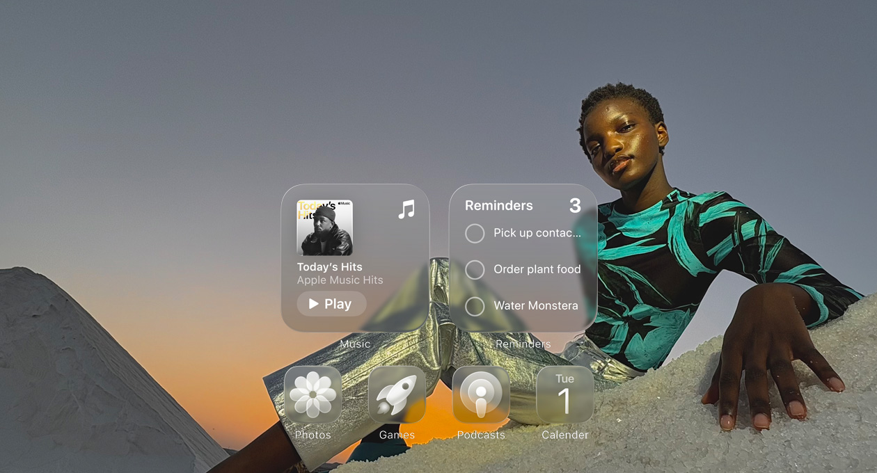 Liquid Glass képernyő az Apple Music, az Emlékeztetők, a Fotók, a Játékok, a Podcastok és a Naptár app áttetsző ikonjaival, amelyeken átszűrődik a háttérkép