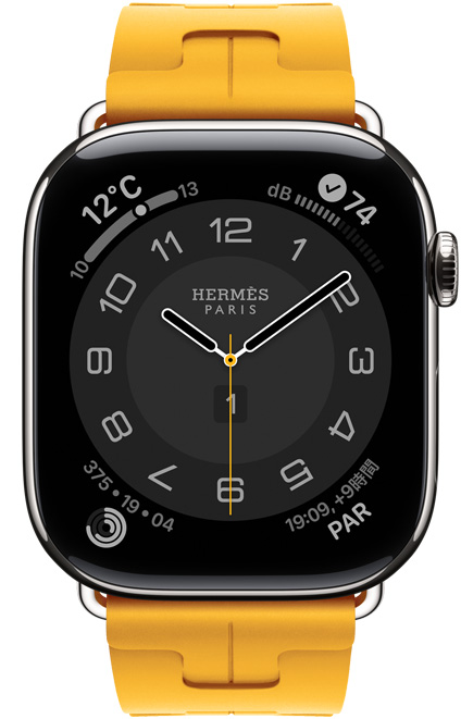 シルバーチタニウムケースのApple Watch Hermès Series 11、アナログデザインのCirculaire文字盤に、時針、分針、秒針と、天気、アクティビティリング、パリ時間、ノイズのコンプリケーションが表示されている。右側面の外観、Digital Crown。フルオロエラストマーラバー素材のキリムシンプルトゥールストラップとの組み合わせ、カラーはジョーヌ（カナリアイエロー）