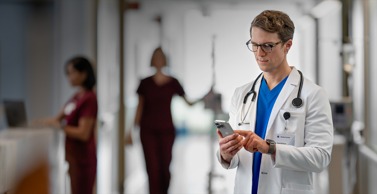 一位男醫護人員在醫院看他的 iPhone。