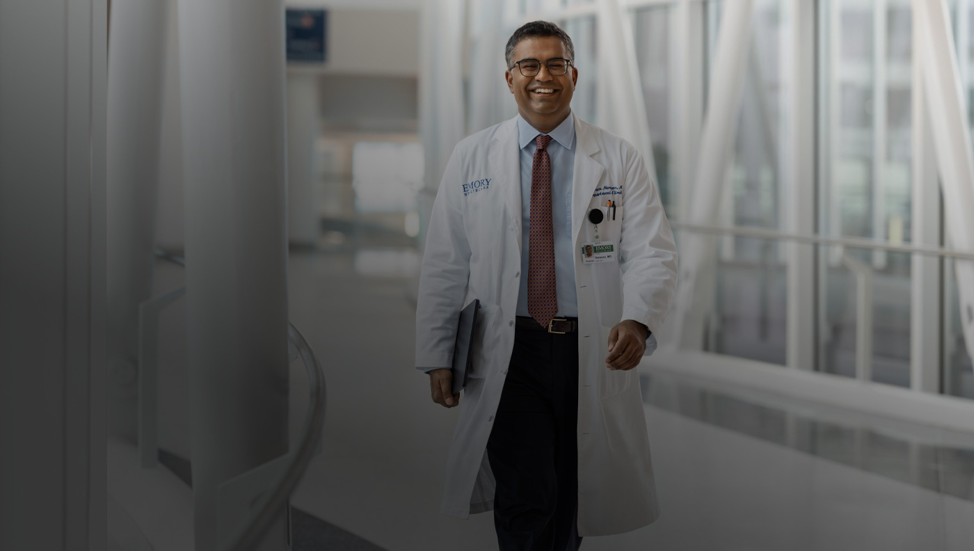 一個醫生正在行走，右手拿著一部 MacBook。 