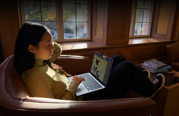 Iemand zit in een fauteuil en werkt op een MacBook Air