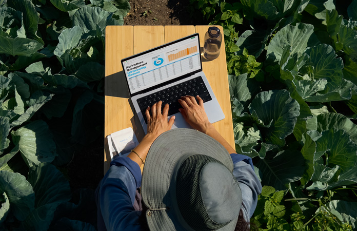Iemand gebruikt een MacBook Pro met display met nanotextuur in de buitenlucht, ter illustratie van het feit dat je met dit type display minder last hebt van schitteringen