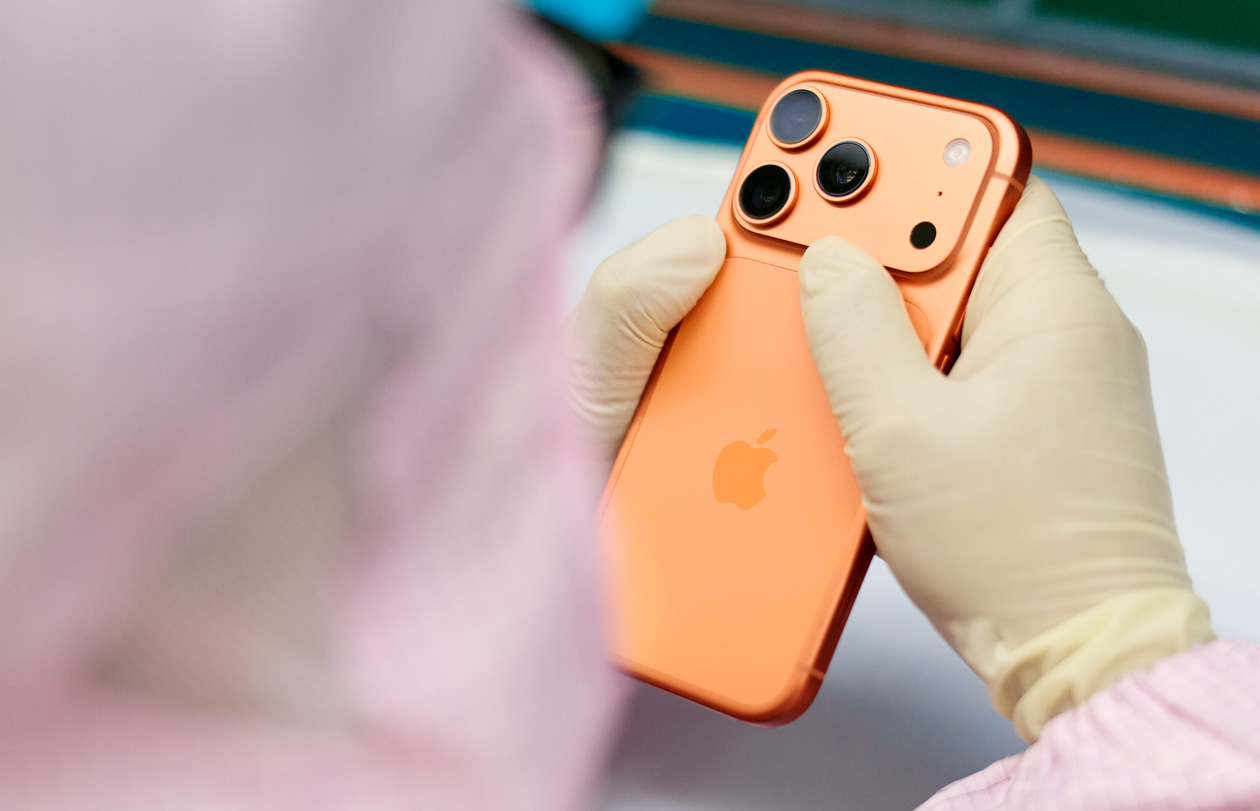 Een medewerker in volledig beschermende werkkleding inspecteert een iPhone op een werkplek