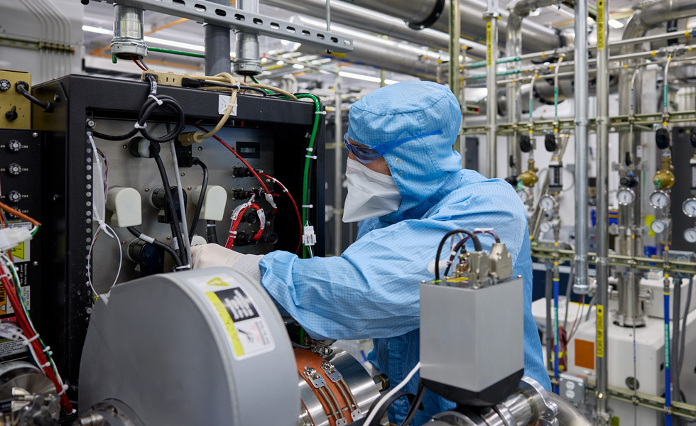 Een medewerker in volledig beschermende werkkleding inspecteert machines