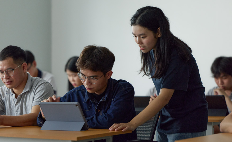 Twee mensen in een klaslokaal werken samen op een Apple tablet