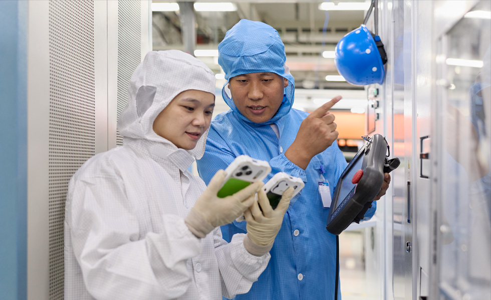 Twee mensen in volledig beschermende werkkleding werken samen op twee iPhones