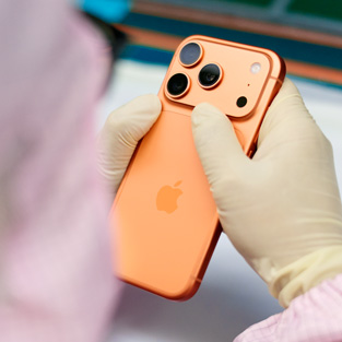 Een medewerker in volledig beschermende werkkleding inspecteert een iPhone op een werkplek