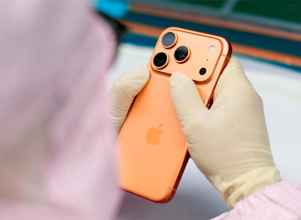 Een medewerker in volledig beschermende werkkleding inspecteert een iPhone op een werkplek